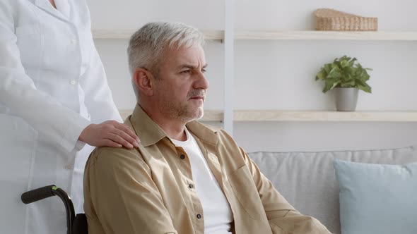 Assistant Touching Disabled Man's Shoulder Supporting Patient During Rehabilitation Indoors alt