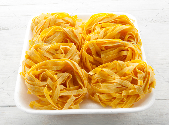 Uncooked rolls of Italian tagliatelle noodles - Stock Photo - Images