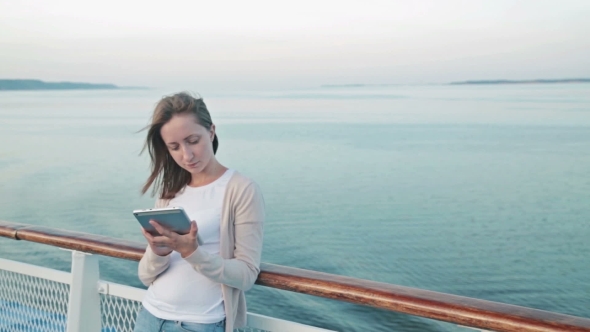 Woman Using Tablet on Deck of Cruise Ship at Sunrise
