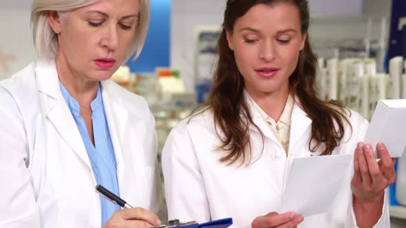 Pharmacists maintaining a record of medicine on clipboard alt