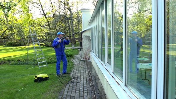 Professional Worker Cleaning Dirty Windows with High Pressure Water Jet