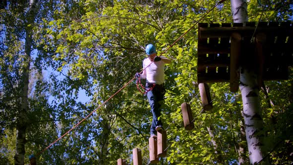 A Man Walks on Logs Suspended in the Air Between Trees in the Forest alt
