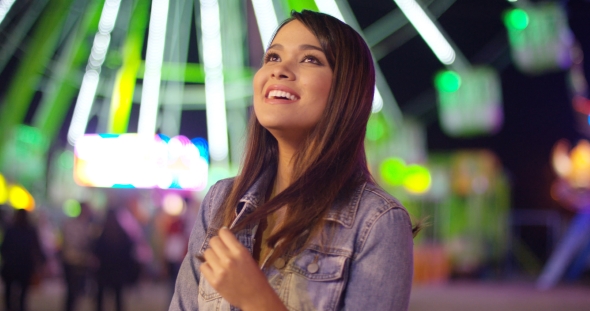 Young Woman at Carnival Stands Looking Up in Awe alt