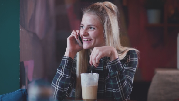 Pretty Young Girl Drinking Coffee and Talking Using Smartphone