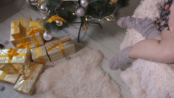 Female Hands Gives a Gift, Christmas Present Into Camera. Gifts Under Christmas Tree. Slider Shot. alt