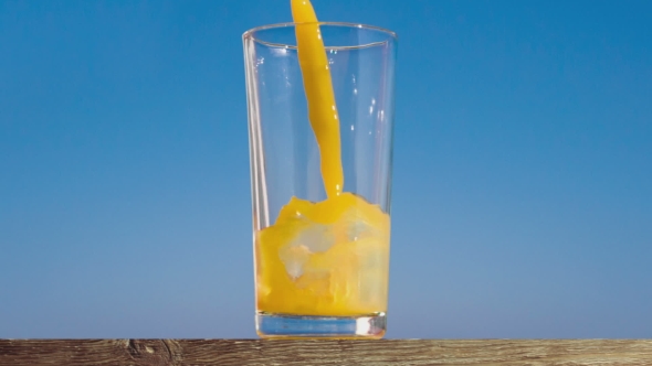 Pouring a Glass of Orange Juice Creating Splash