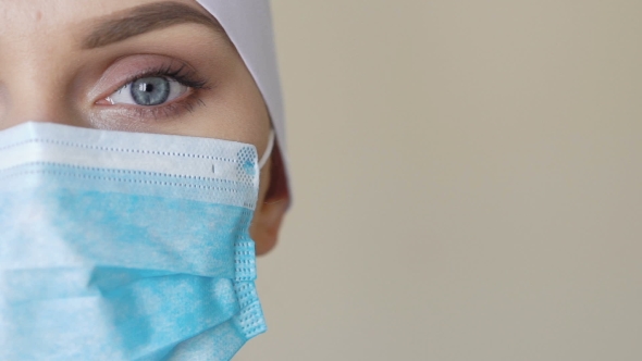Female Medical Worker Wearing Face Mask Looking Into Camera alt