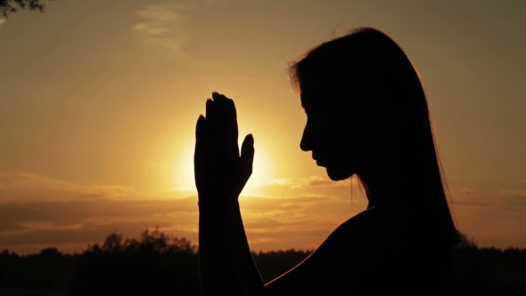 Young Woman Praying in the Forest at Sunset