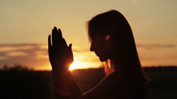 Young Woman Praying in the Forest at Sunset