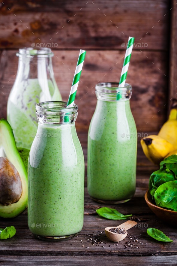 healthy green smoothie with banana, spinach, avocado and chia seeds in glass bottles