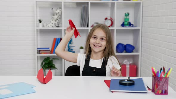 Happy Schoolgirl Having Fun Playing with Paper Plane at School Lesson in Classroom Schooler alt