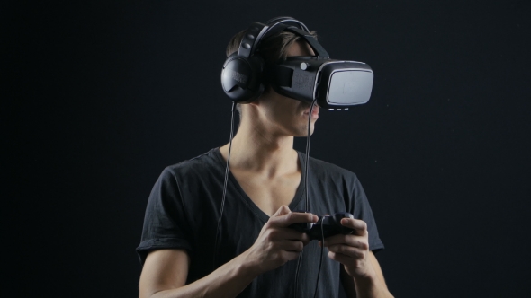 Virtual Reality Game. Man with Pleasure Uses Head-mounted Display in Dark Room alt