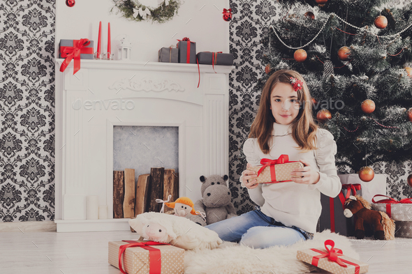 Beautiful girl in santa hat unwrapping christmas presents - Stock Photo - Images