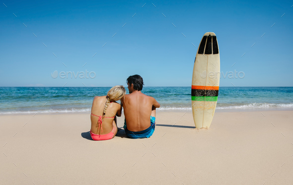 Couple relaxing on the sea shore with surfboard - Stock Photo - Images