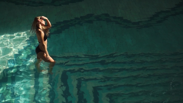 Sexy Woman in the Hotel Pool Playing with Her Hair, Looking at the Sunset Sunrise. Beautiful Curves