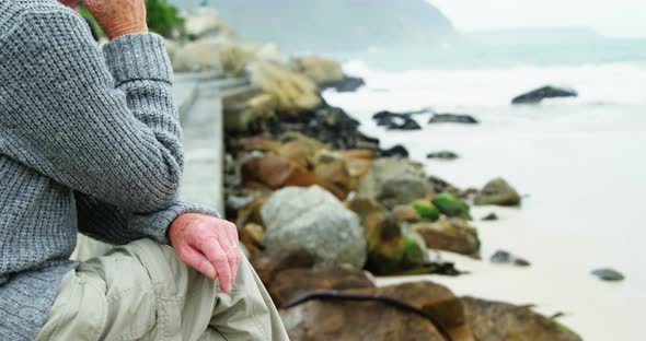 Senior man sitting on beach alt