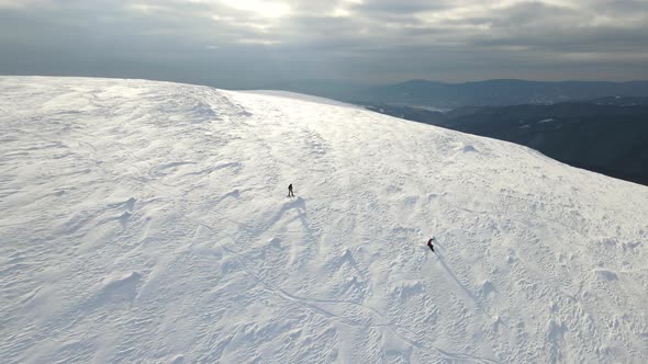 Two Snowboarders Descend From a Snowcovered Mountain