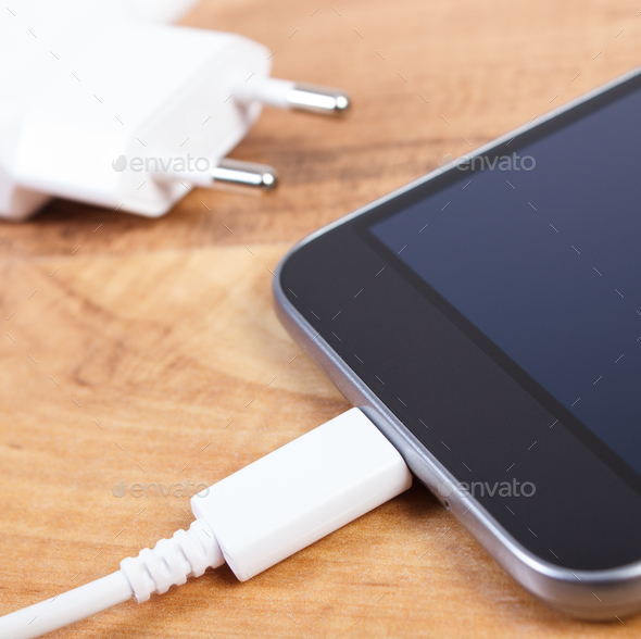 Mobile phone with connected plug of charger, smartphone charging Stock Photo by ratmaner