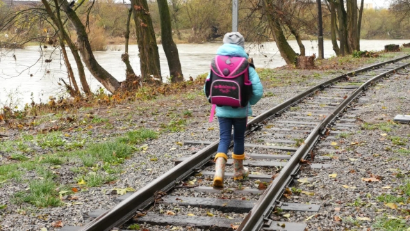 Back View of the Girl Going Along the Railway. First Grader Goes By Rail Sleepers alt