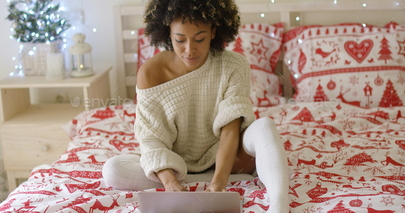 Woman in oversized sweater on bed using laptop Stock Photo by Daniel_Dash