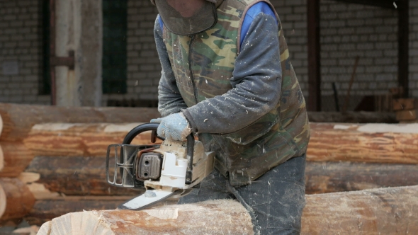 Man Cuts Wood Chainsaw for Future Home. Protective Face Mask on the Face of the Builder