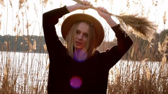 Caucasian Blonde Woman Waving Pampas Grass with Beige Hat in Black Sweater in the Countryside alt