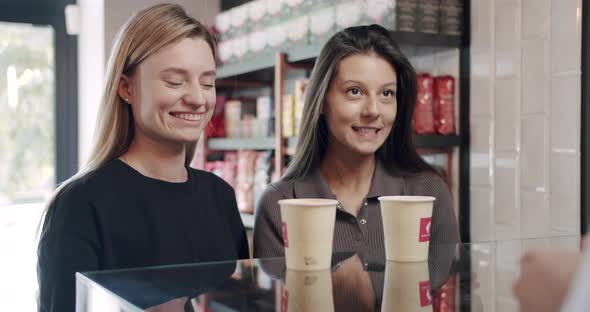 Bartender Serves Two Beautiful Girls with Coffee in the Cafe Payment By Card alt