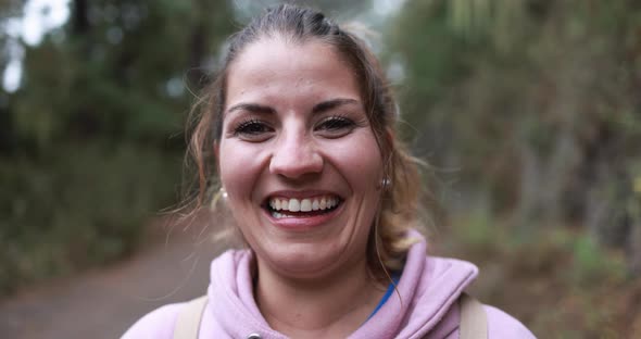 Caucasian young woman smiling on camera during hiking day into the woods alt