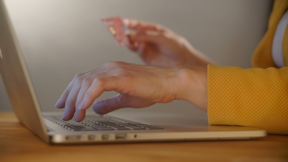 Woman's Hands Holding a Credit Card and Using Computer Keyboard for Online Shopping
