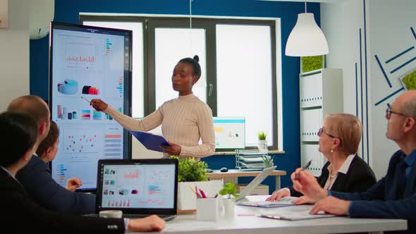 Black Woman Worker Explaning Company Statistics in Front of Colleagues alt