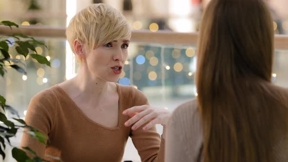 Closeup Middleaged Blonde Woman with Short Haircut Talking Chatting with Unrecognizable Lady Girl alt
