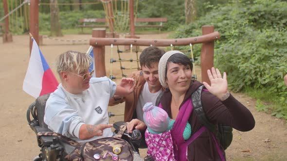 Family member with a disability in a wheelchair meets with relatives. Outdoors. alt