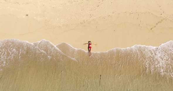 Aerial Top View of Beautiful Girl in Red Bikini Lying on the Beach Sand with Calm Waves