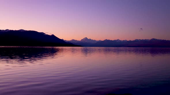 Wide sunset time lapse of Mount Cook and Lake Pukaki with reflections of bright clear mountain skyli alt
