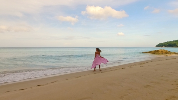 Aerial: Lonely Girl Walks on the Beach Near Waves. alt