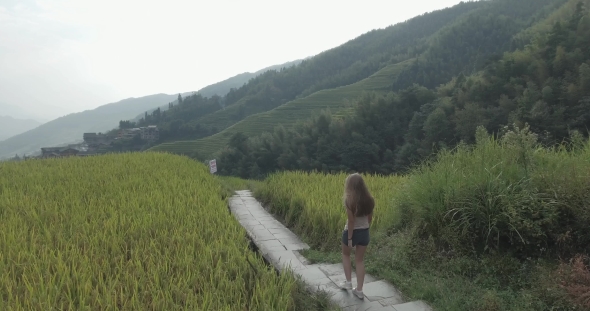 Young Woman Walking Along Terraced Rice Field