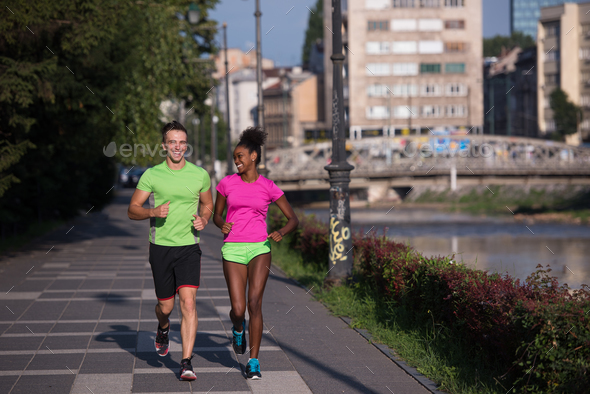 young smiling multiethnic couple jogging in the city - Stock Photo - Images
