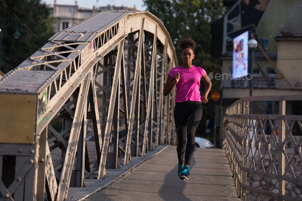 african american woman running across the bridge - Stock Photo - Images