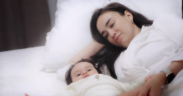 Mom is Lying on the Bed with Her Baby Daughter