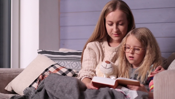 Mother and Daughter Reading Bedtime Story on Sofa alt