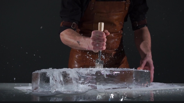 Barman with Strong Arms Crushing Ice with Special Fork and Breaking Off a Big Piece of Ice