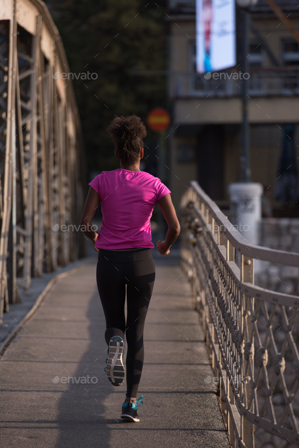 african american woman running across the bridge - Stock Photo - Images
