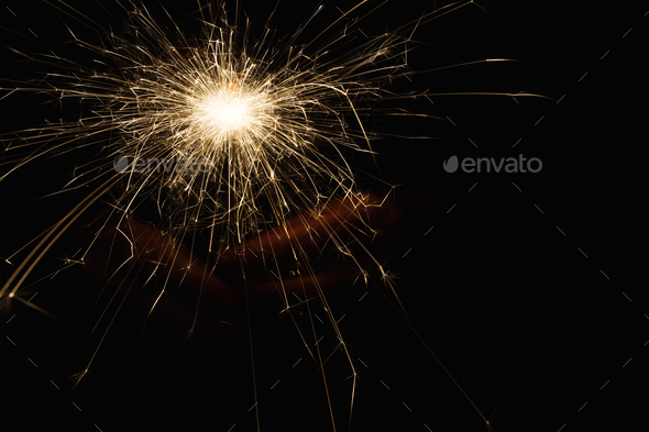 New year party sparkler in female hands on black background - Stock Photo - Images
