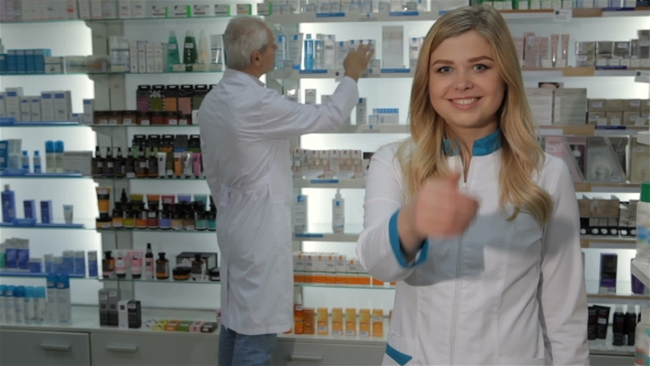 Female Pharmacist Shows Her Thumb Up at the Drugstore alt