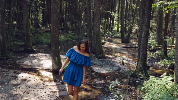 Young Girl with White Skin, on a Stream with Clear Water in a Blue Dress Is Among Barefoot in the