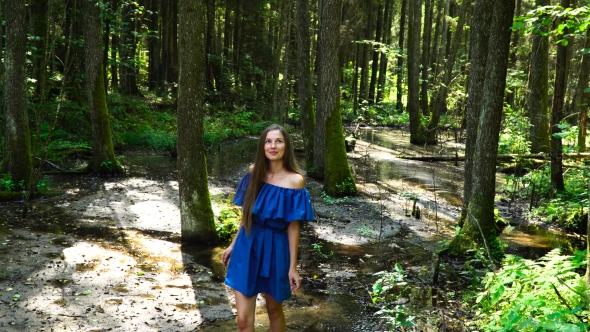 Young Girl with White Skin, on a Stream with Clear Water in a Blue Dress Is Among Barefoot 