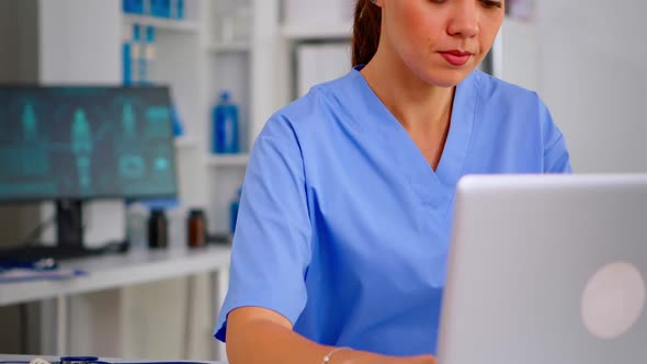 Portrait of Nurse Looking at Camera Smiling After Typing on Laptop Sitting alt
