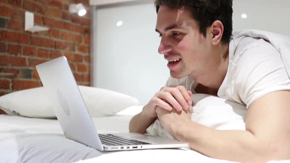 Online Video Chat on Laptop By Man Lying in Bed at Night alt
