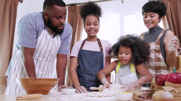 African American Mom, dad, and two daughters helping thresh dough together