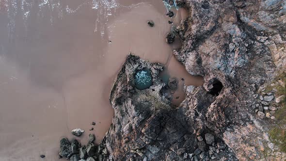 AERIAL: Slow descend over swirling large rockpool, Blue Pool Bay, 4k Drone alt
